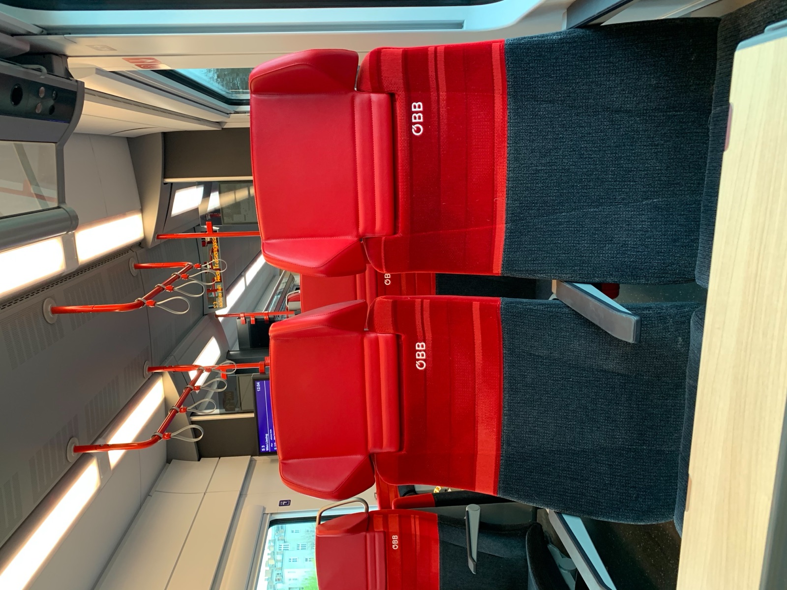 Innenraum eines ÖBB Cityjet mit Sitzreihen und Gepäckablagen
